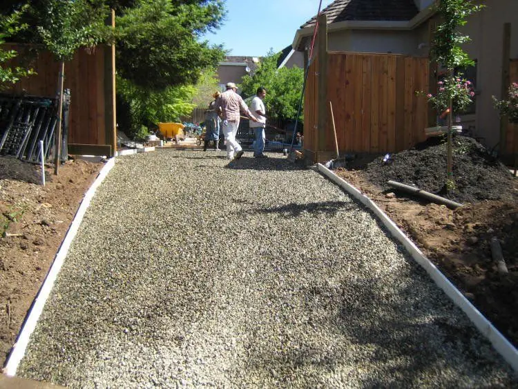 Fresh residential driveway concrete between fences.